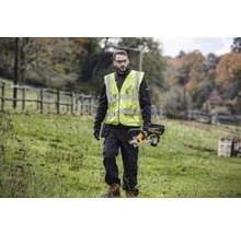 Mann mit Sicherheitsweste und Akku-Kettensäge im Freien