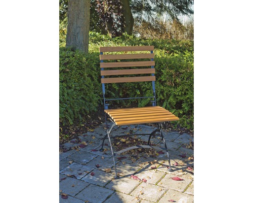 Gartenszene mit einem einzelnen Holzklappstuhl auf einer Terrasse