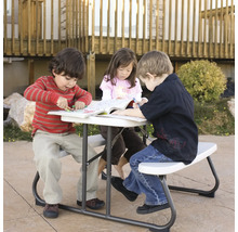 Kinder sitzen an einem Picknicktisch und malen in Büchern.