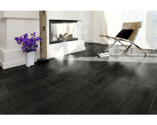 Wohnzimmer mit dunklem Fliesenboden, Kamin und Sessel.