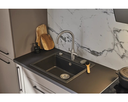 Küchenszene mit Spüle, Armatur und Küchenutensilien auf einer dunklen Arbeitsplatte