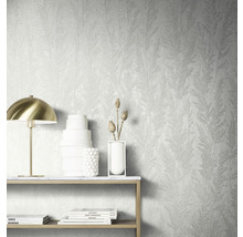 Wandgestaltung mit strukturierter Tapete mit Pflanzenmuster, Tisch mit Dekoration und Lampe