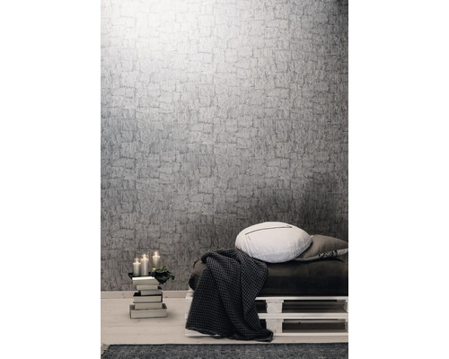 Wohnraum mit grauer Struktur Tapete, Kissen und Wohndecke auf einer Palette