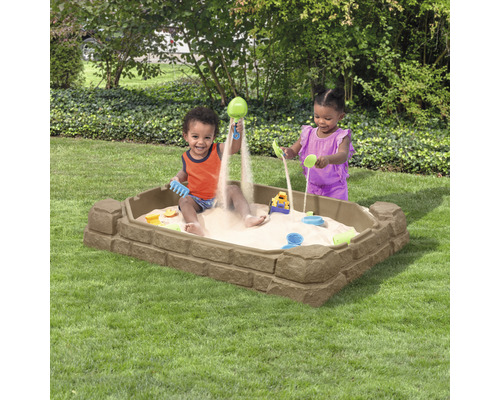 Sandkasten aus Kunststoff mit spielenden Kindern im Garten.