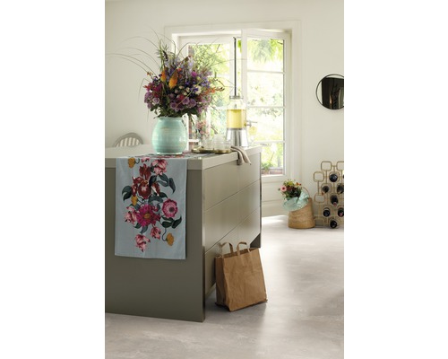 Dekoratives Arrangement in einer hellen Küche mit Blumen, Getränkespender und Stoffläufer