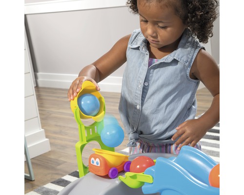 Ein Kind spielt mit einer Spielzeugballbahn mit Fahrzeugen.