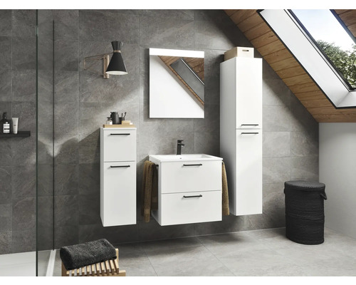 Helles Badezimmer mit Waschtisch, Spiegel, Hochschrank, Wandschrank und Wäschekorb unter einem Dachfenster