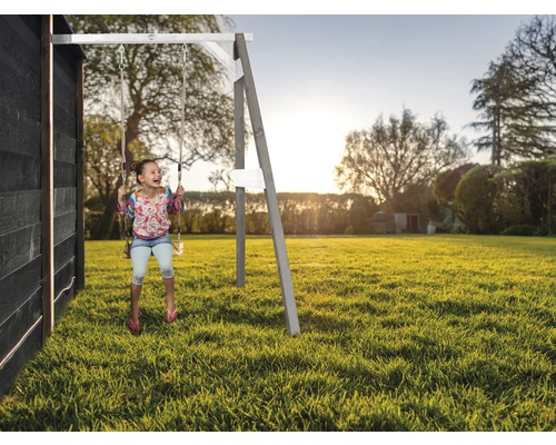 Mädchen schwingt auf einer Holzschaukel im Garten