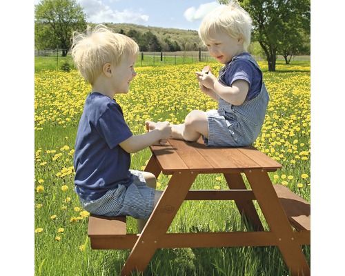 Zwei Kinder sitzen an einem Picknicktisch aus Holz im Freien.