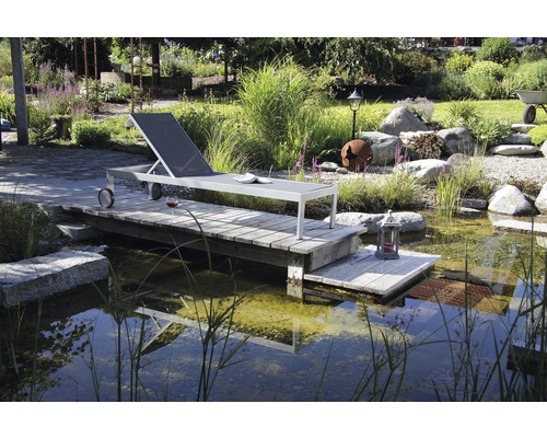 Szene mit einem Garten mit einem Teich und einem Liegestuhl auf einem Holzsteg