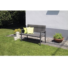 Gartenbank aus Polyrattan mit Kissen auf einer Rasenfläche