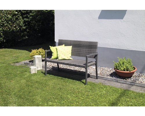 Gartenbank aus Polyrattan mit Kissen auf einer Rasenfläche