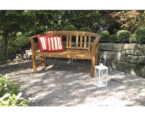 Holzgartenbank mit zwei Kissen und einer Laterne im Garten