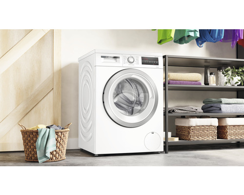 Weiße Bosch Waschmaschine in einem Waschraum mit Wäschekorb und Regal.