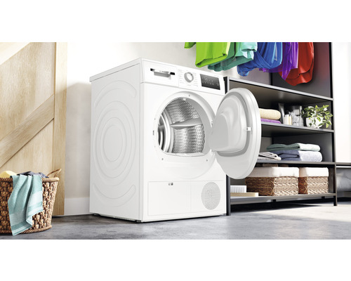 Freistehender Kondenstrockner mit geöffneter Tür in einem Wäscheraum.