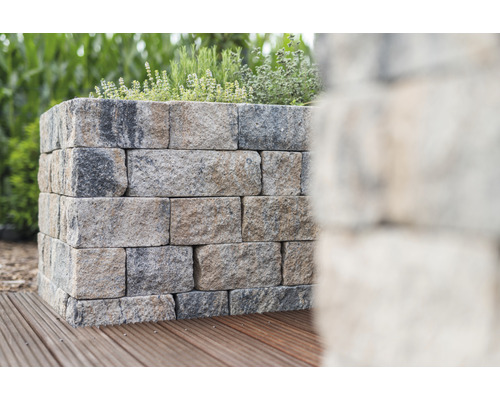 Stützmauer aus Steinblöcken mit Pflanzen darauf auf Holzterrasse