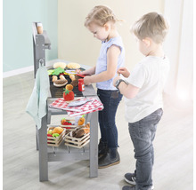 Zwei Kinder spielen mit einem Spielzeuggrill mit Stofflebensmitteln.