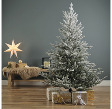 Dekorierter, schneebedeckter Weihnachtsbaum mit Geschenken im Wohnzimmer