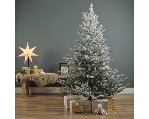 Dekorierter, schneebedeckter Weihnachtsbaum mit Geschenken im Wohnzimmer