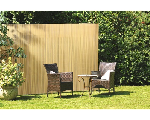 Gartenbereich mit Sichtschutzzaun aus Bambus, zwei Rattansesseln und kleinem Tisch auf einer Rasenfläche