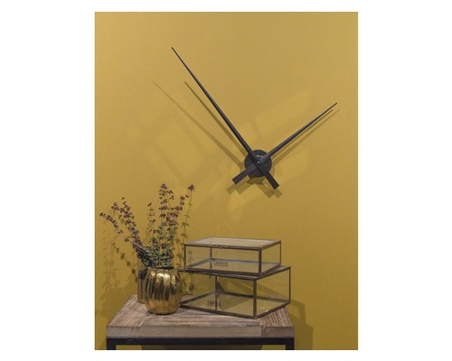 Dekorative Szene mit Wanduhr, goldenem Blumentopf und Glasboxen auf einem Tisch.