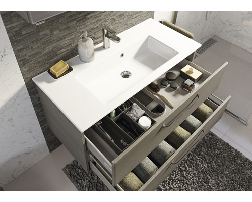 Waschtischunterschrank mit Waschbecken, Armatur und offenen Schubladen zur Aufbewahrung von Badutensilien und Handtüchern.