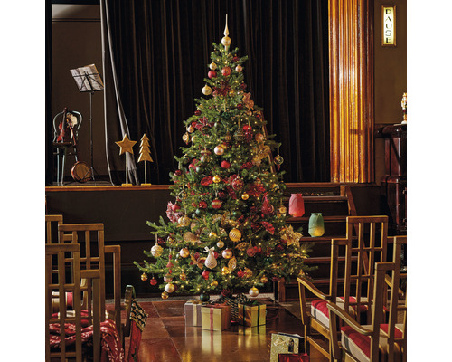 Festlich geschmückter Weihnachtsbaum mit Geschenken in einem Raum mit Bühnenbild