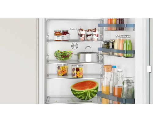 Offener Kühlschrank gefüllt mit Lebensmitteln wie Wassermelone, Salaten, Desserts und Getränken