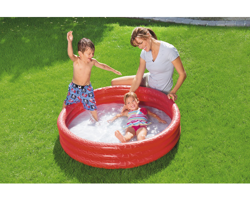 Aufblasbarer Pool mit spielenden Kindern und einer Erwachsenen im Garten