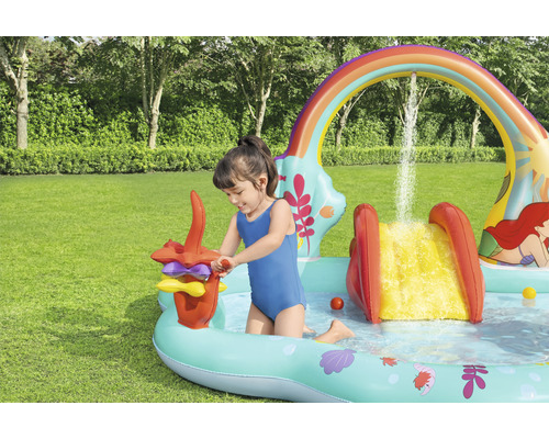 Kind spielt im aufblasbaren Planschbecken mit Rutsche und Wasserspielen im Garten