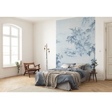 Schlafzimmer mit blau gemusterter Fototapete, Bett, Leselampe und Holzstuhl