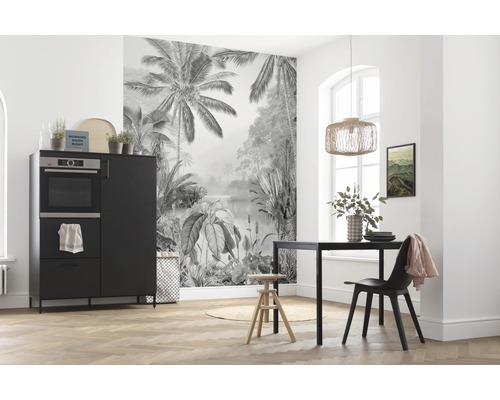 Esszimmer mit schwarzem Esstisch, Stuhl und Sideboard vor einer Fototapete mit Dschungelmotiv.