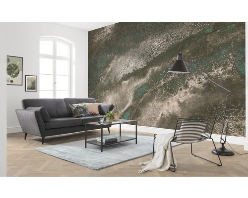 Wohnzimmer mit grauer Couch, Tisch, Lampe und Fototapete mit abstraktem Muster