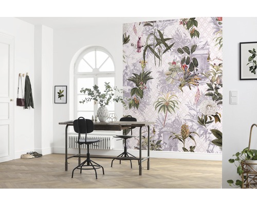 Ein heller Raum mit einem Tisch, Stühlen und einer Wand mit botanischer Tapete.