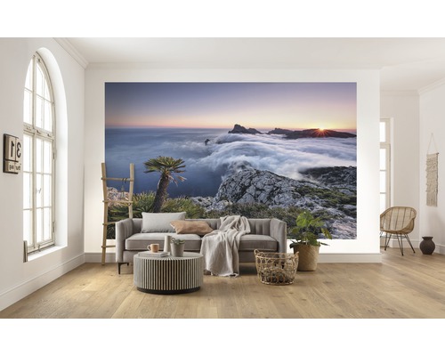 Wohnraum mit Fototapete einer Berglandschaft im Sonnenaufgang über den Wolken