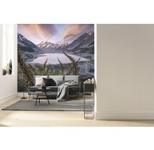 Wohnzimmer mit Fototapete einer Berglandschaft mit See und Sofa.