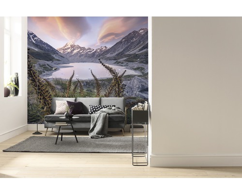 Wohnzimmer mit Fototapete einer Berglandschaft mit See und Sofa.