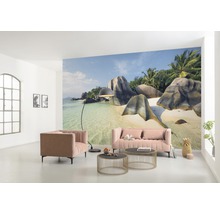 Wohnzimmer mit Fototapete eines tropischen Strandes, Sofa, Sessel und Couchtischen