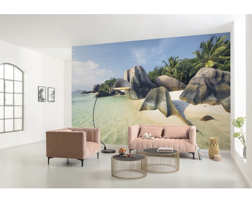 Wohnzimmer mit Fototapete eines tropischen Strandes, Sofa, Sessel und Couchtischen