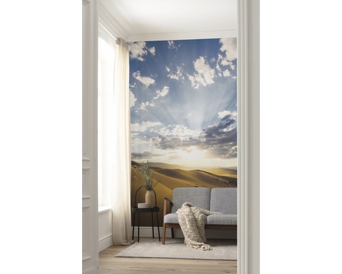 Wohnzimmer mit Fototapete, die eine Wüstenlandschaft mit Himmel und Wolken zeigt