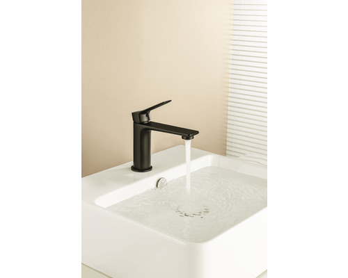 Schwarze Armatur auf einem weißen Waschbecken mit fließendem Wasser.