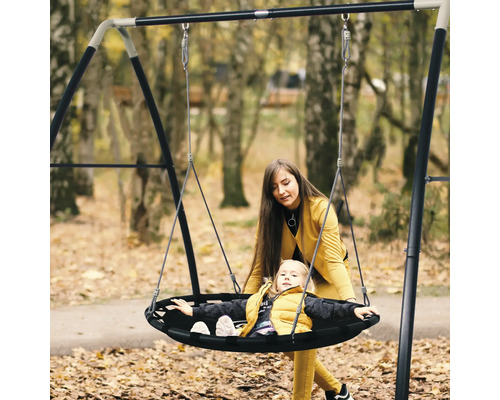 Mutter und Kind auf einer runden Schaukel im Garten