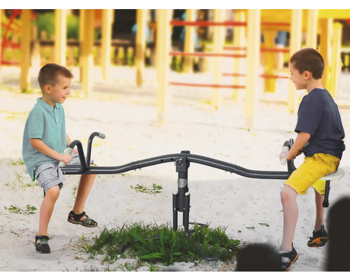 Zwei Kinder spielen auf einer Wippe auf einem Spielplatz.