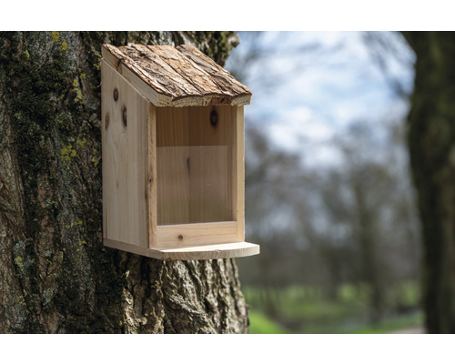 Vogelhaus aus Holz mit Rindendach an einem Baum befestigt