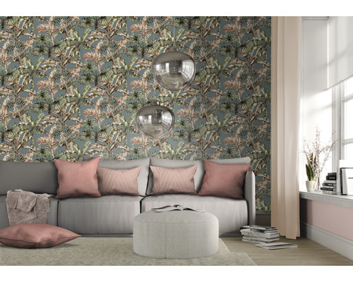 Wohnzimmer mit Couch, Kissen und Deko vor einer Tapete mit Pflanzenmuster