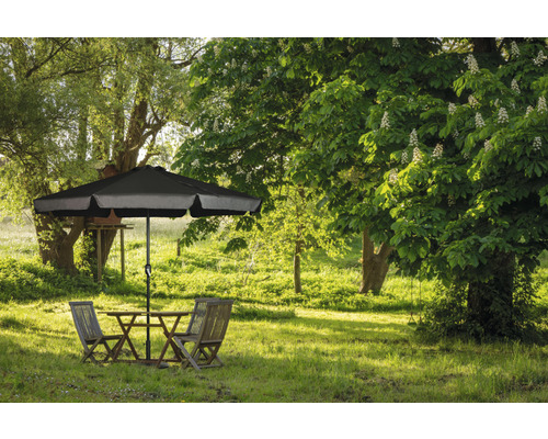 Gartenszene mit Tisch, Stühlen und Sonnenschirm auf einer grünen Wiese