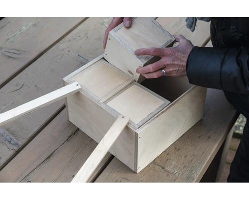 Holzkiste mit Fächern und herausnehmbaren Einsätzen wird von Hand bestückt