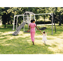Spielplatz mit Turm, Rutsche und Schaukel im Garten, eine Frau hält die Hand eines Kindes