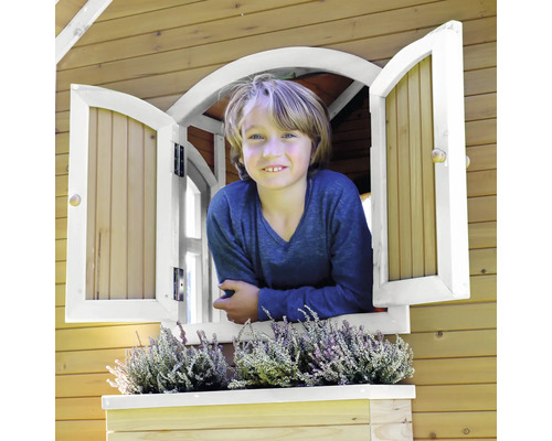 Junge schaut aus dem Fenster eines Holzspielhauses mit Fensterkasten