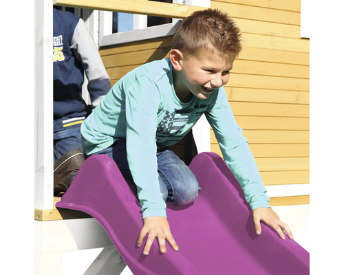 Junge rutscht auf einer Kunststoffrutsche eines Spielhauses.